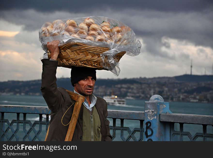 Basket on Man&#x27;s Head Under Cloudy Sky