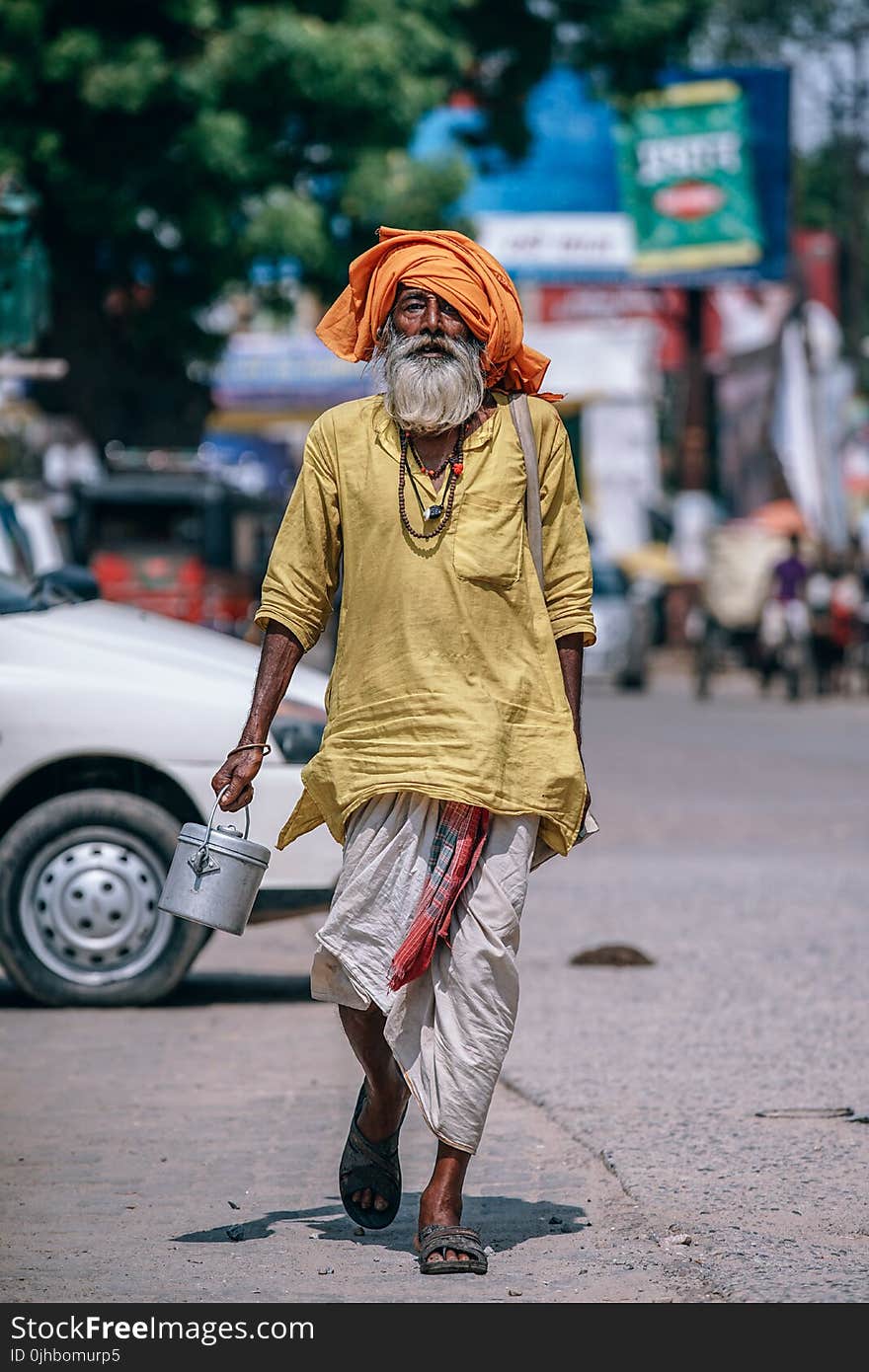 Man Walking on Street Carrying Metal Bucket