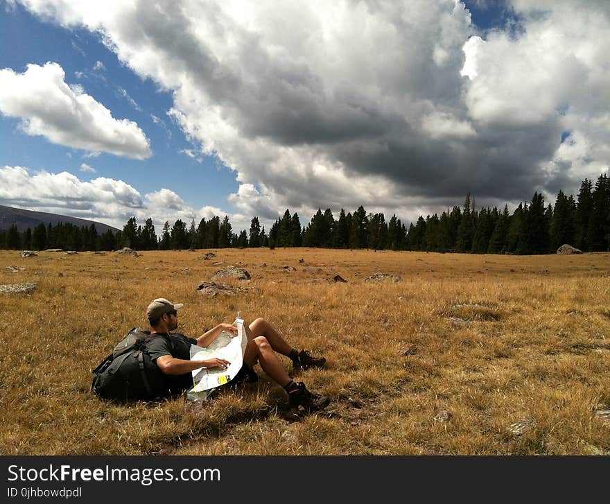 Man in Black Shirt With Black Backpack Lying on Brown Grass Photo