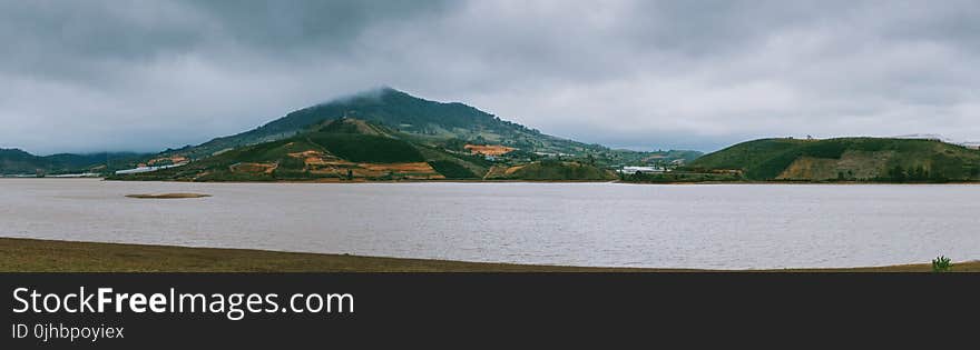 Green Mountain Beside Ocean during Cloudy Day