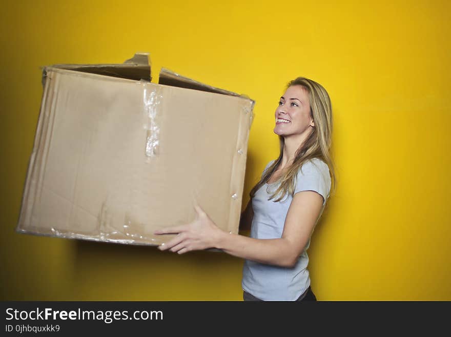 Woman In Grey Shirt Holding Brown Cardboard Box