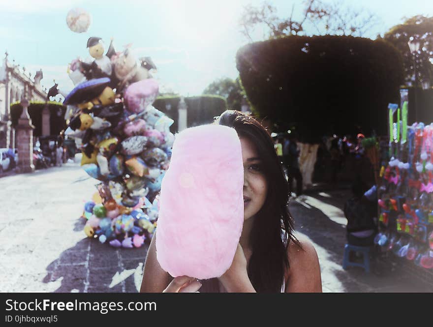 Woman Holding Cotton Candy With Balloons in Background