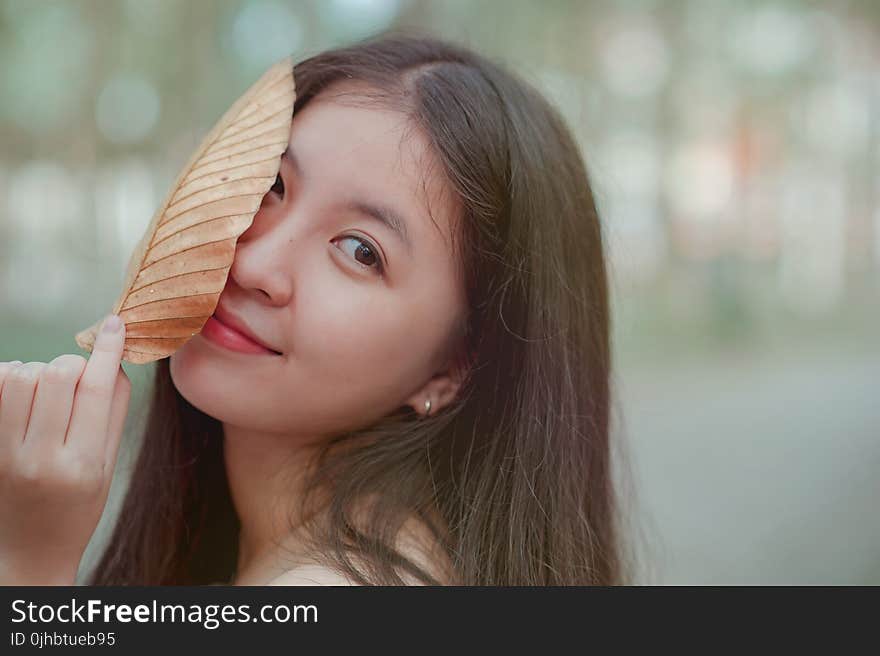 Photo of a Woman Holding a Dry Leaf