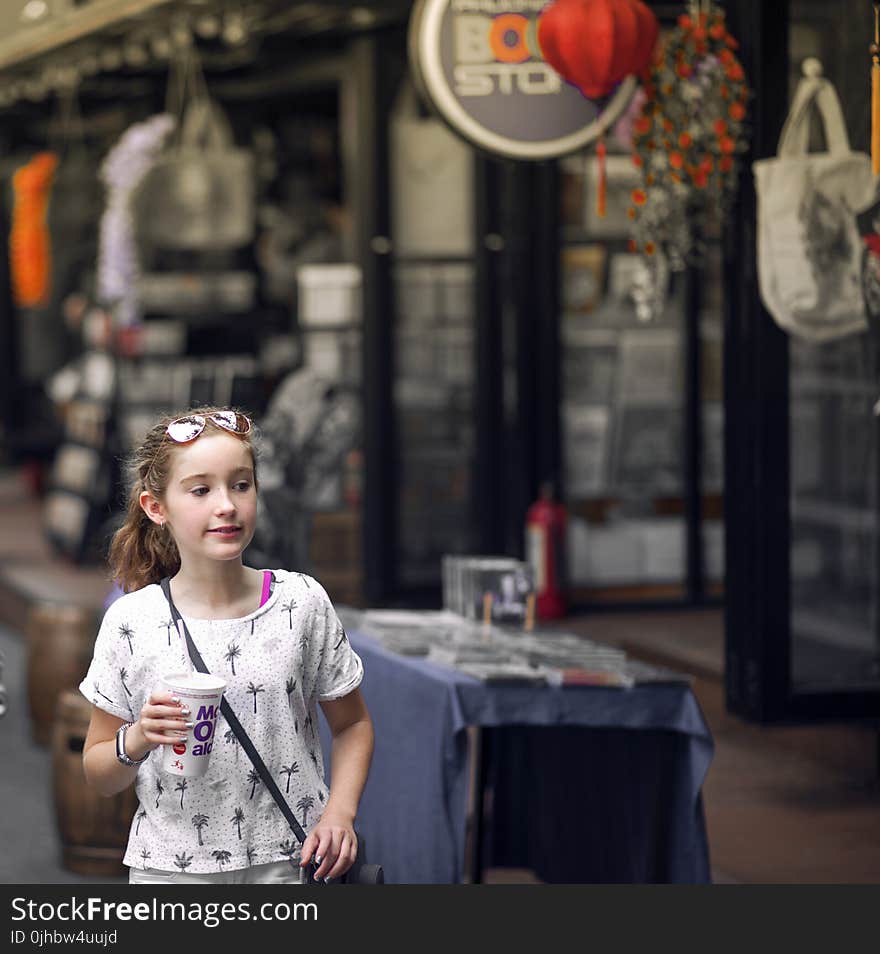 Selective Focus Photo of Girl Wearing Gray and Black Tree Print Holding Mcdonald Plastic Cup