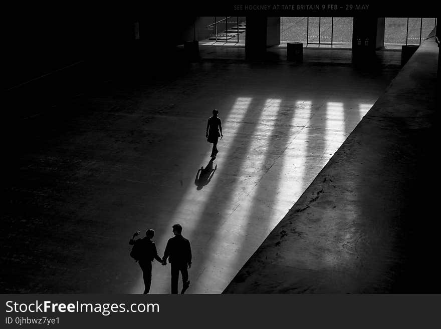 Grayscale Photo Of Three Men Walking Inside Building