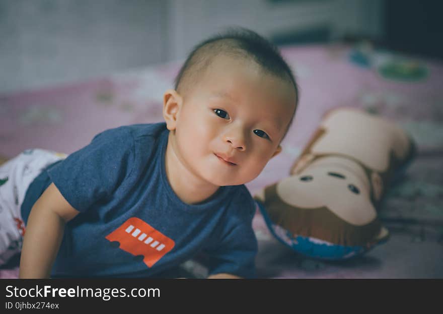 Close-Up Photography of Baby Lying on the Bed Near Bolster Pillow