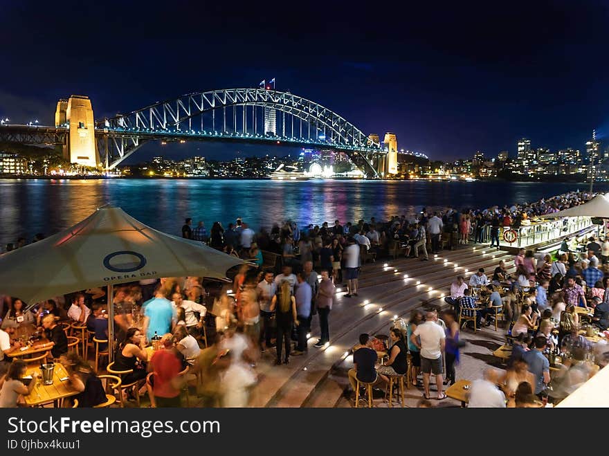 People Sitting and Standing Near Bridge during Nighttime