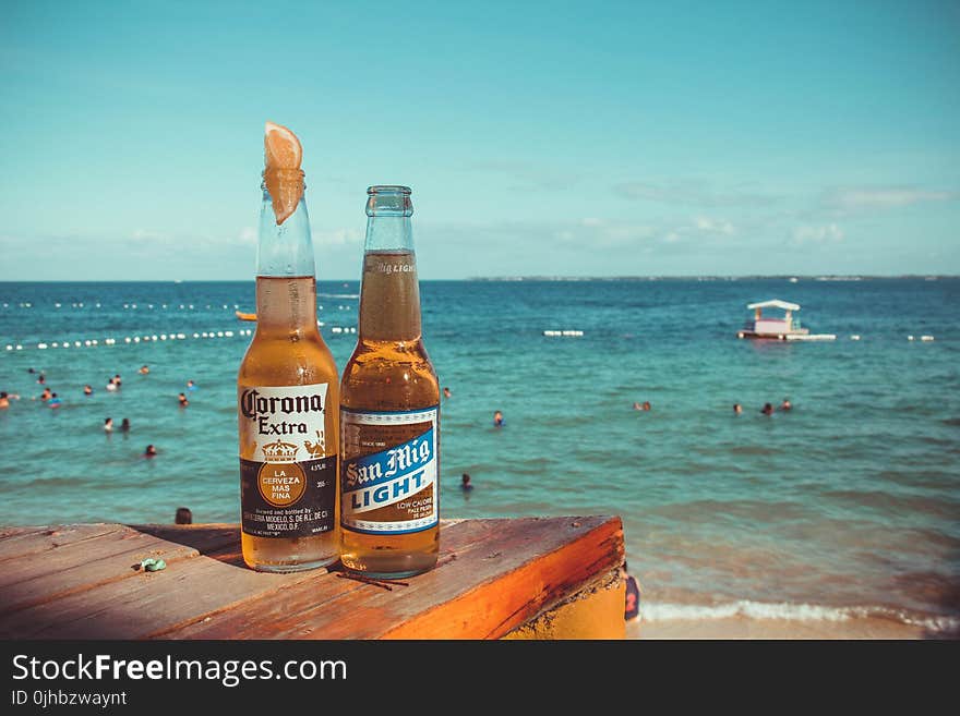 Two Corona Extra and San Mig Light Beers on Top of Brown Wooden Plank Near Beach