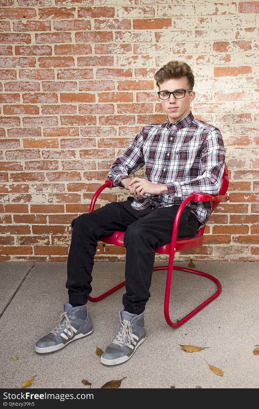 Man Wearing White And Red Long Sleeve Shirt Sitting On Red Steel Armchair