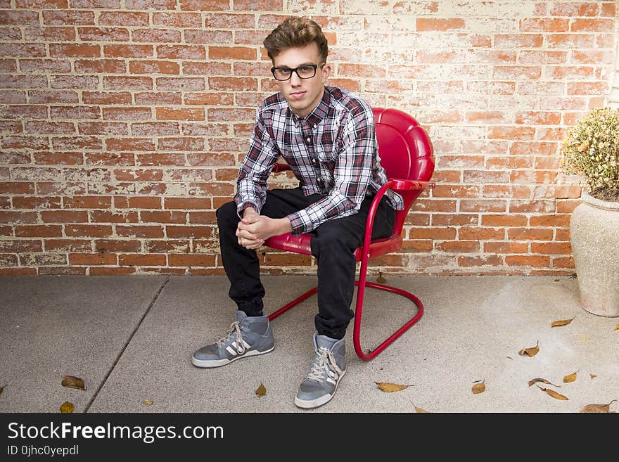 Man In Plaid Long-Sleeved Shirt And Black Pants Sitting On Red Chair