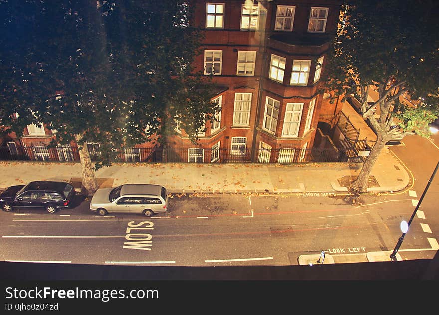 Two Cars Parked Near Brown Concrete Building during Nighttime