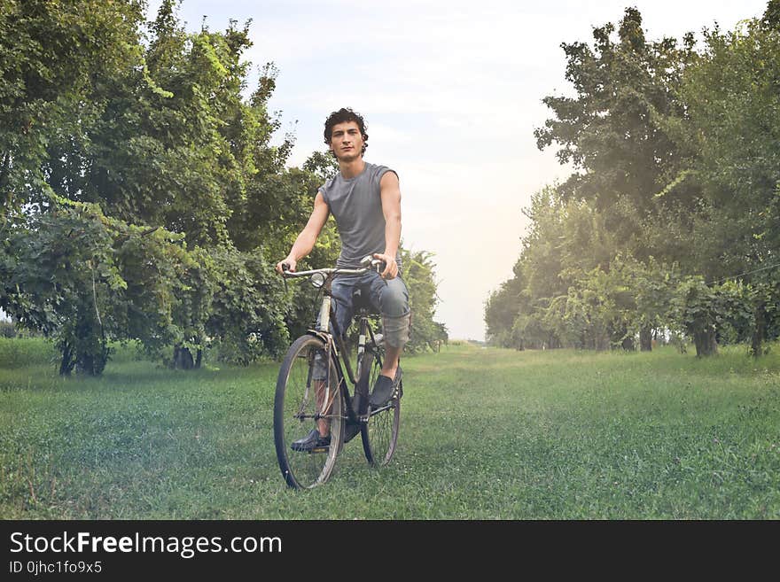 Man in Gray Sleeveless Shirt Riding Bike