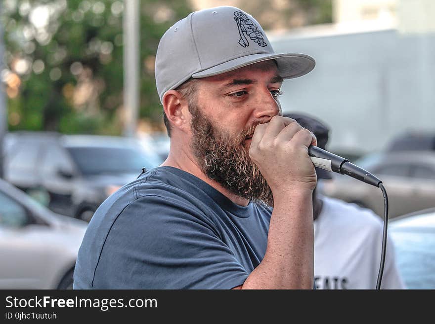 Man In Crew-neck Shirt And Grey Cap Holding Black Corded Microphone