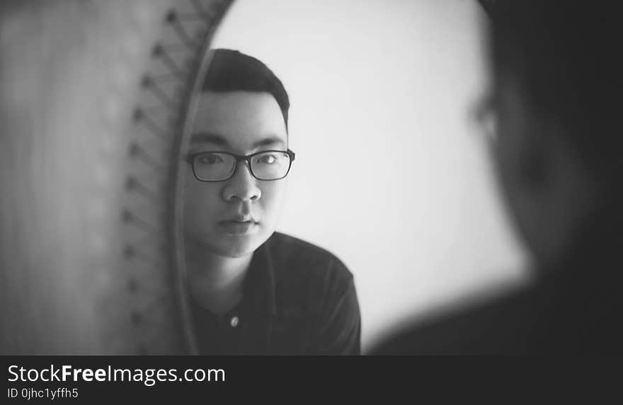 Monochrome Photography of a Man Looking In front of Mirror