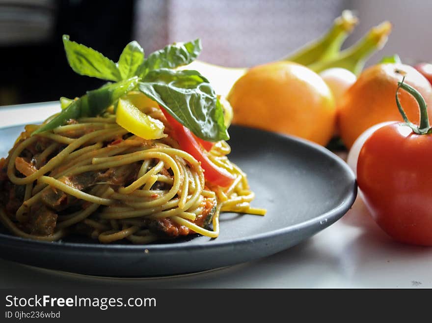 Pasta With Vegetable Dish on Gray Plate Beside Tomato Fruit on White Table