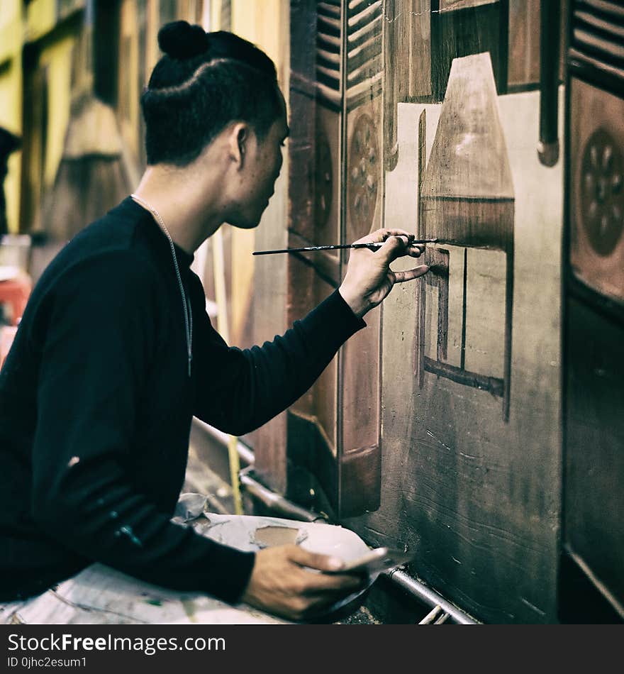 Man In Black Sweatshirt Holding Black Paint Brush Painting the Wall