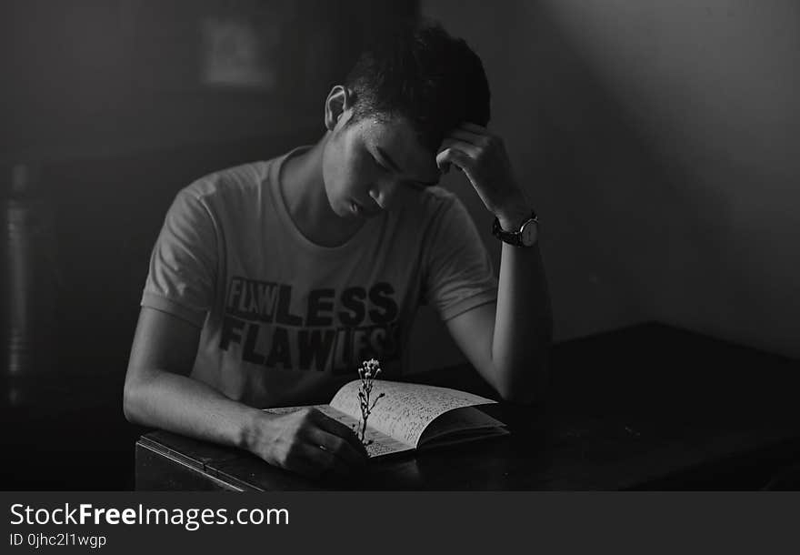 Grayscale Photography of Man in Shirt Reading Notebook