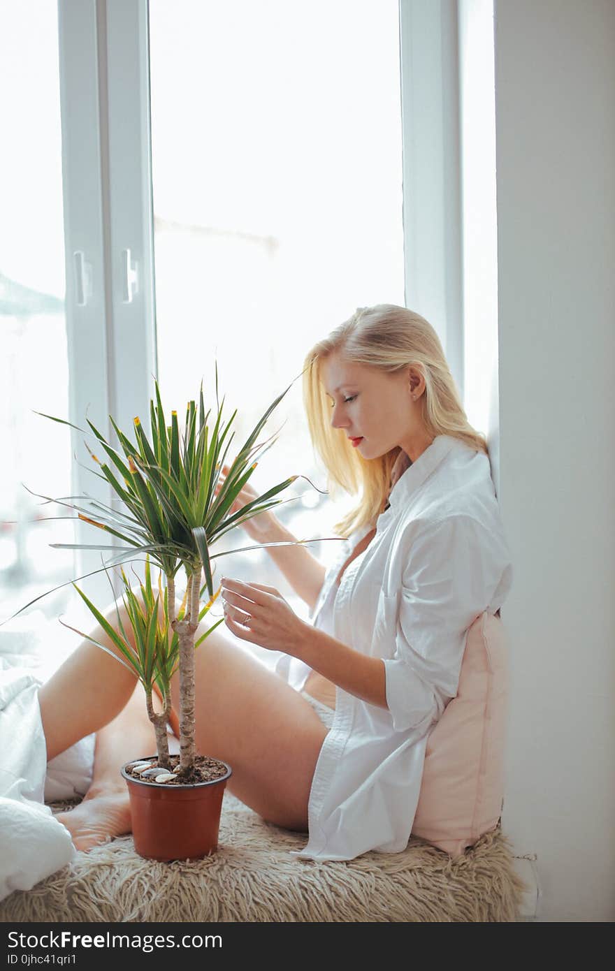 Woman Wearing White Long-sleeved Shirt Sitting Beside Green Plant