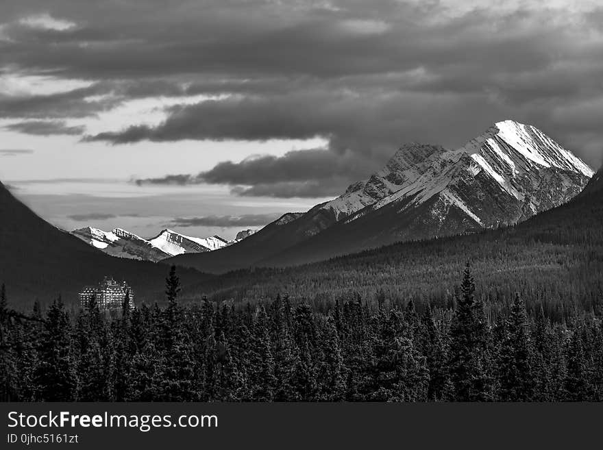 Grayscale Photography Of Snow Covered Mountain Under Cloudy Sky