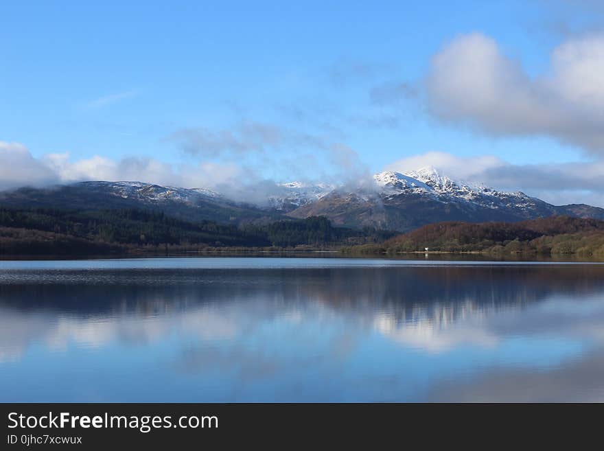 Lake Near Green Trees With Overlooking Mountain Peaks