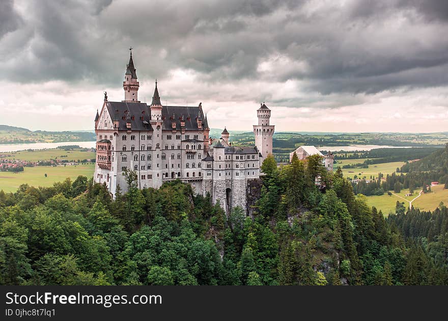 Aerial Photo of White Castle With Green Leafed Tree Under White Cloudy Sky