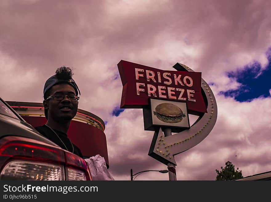 Man In Baseball Cap Near Frisko Freeze Signage