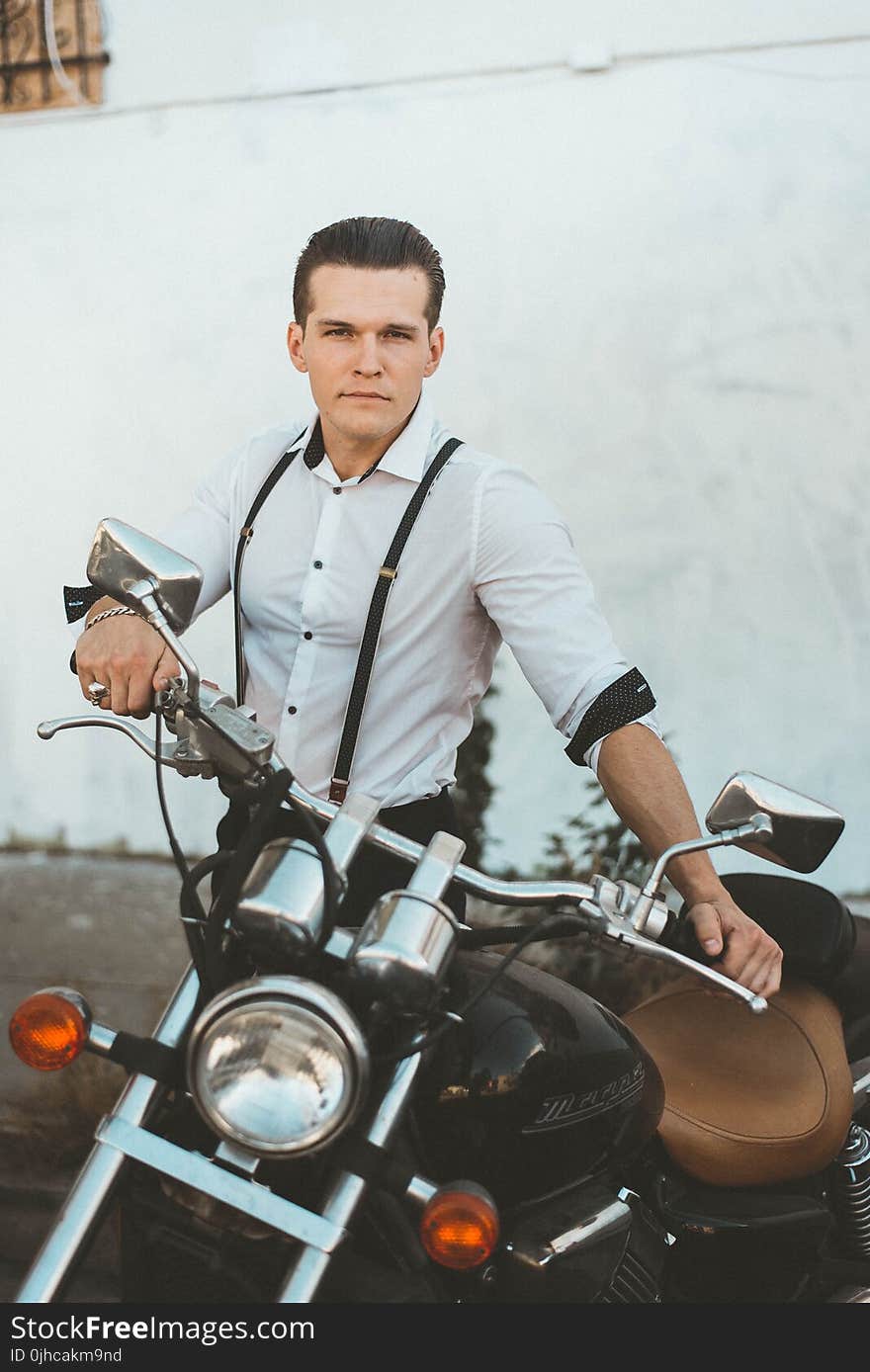 Man in White Dress Shirt Standing Beside Black Motorcycle