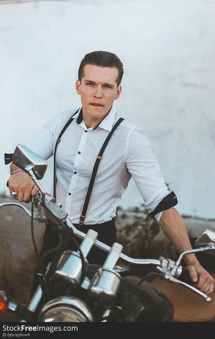 Man in White Dress Shirt With Suspenders Holding Black Motorcycle