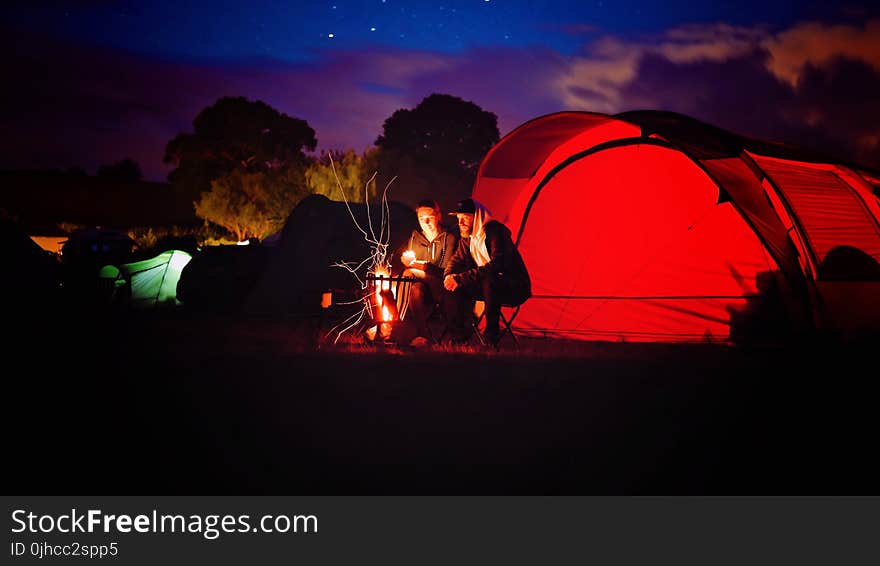 Man and Woman Sitting Beside Bonfire during Nigh Time