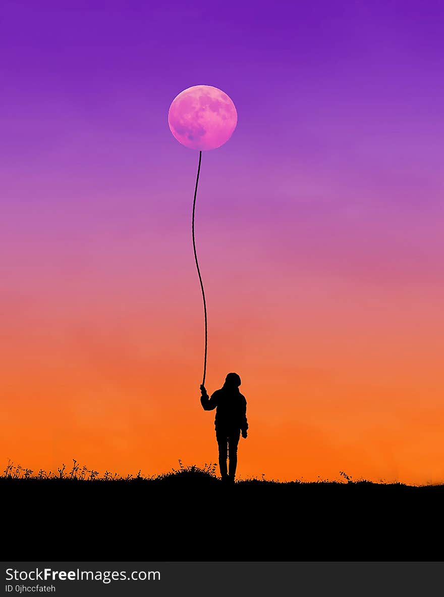 Silhouette of Man Holding String Connected to Moon