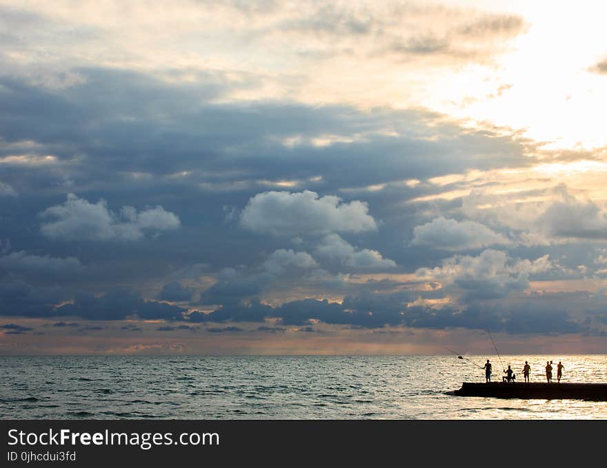 Silhouette Photo of People Standing on Dock Near Sea