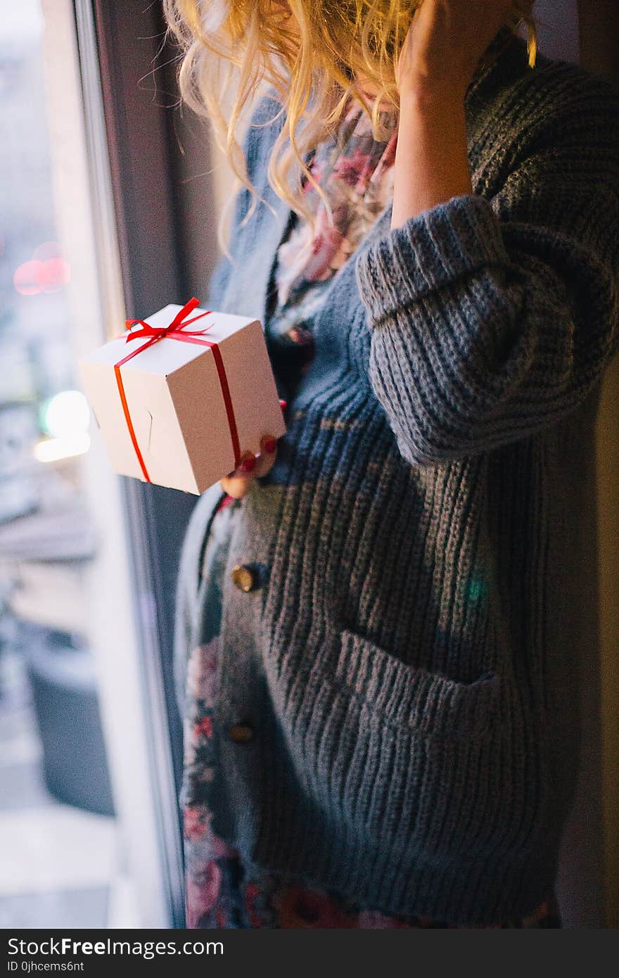 Woman Wearing Blue Knit Cardigan Holding Gift Box Inside Room