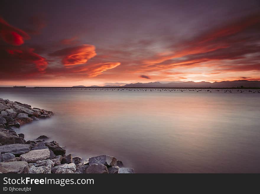 Landscape Photography of Rocks Near Body of Water during Sunset