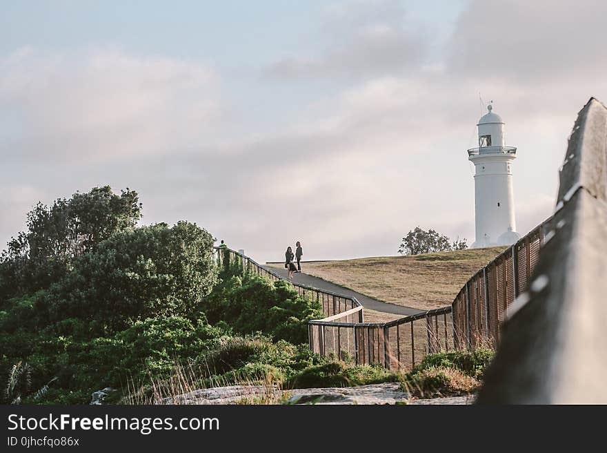 Two Person Standing Near White Lighthouse