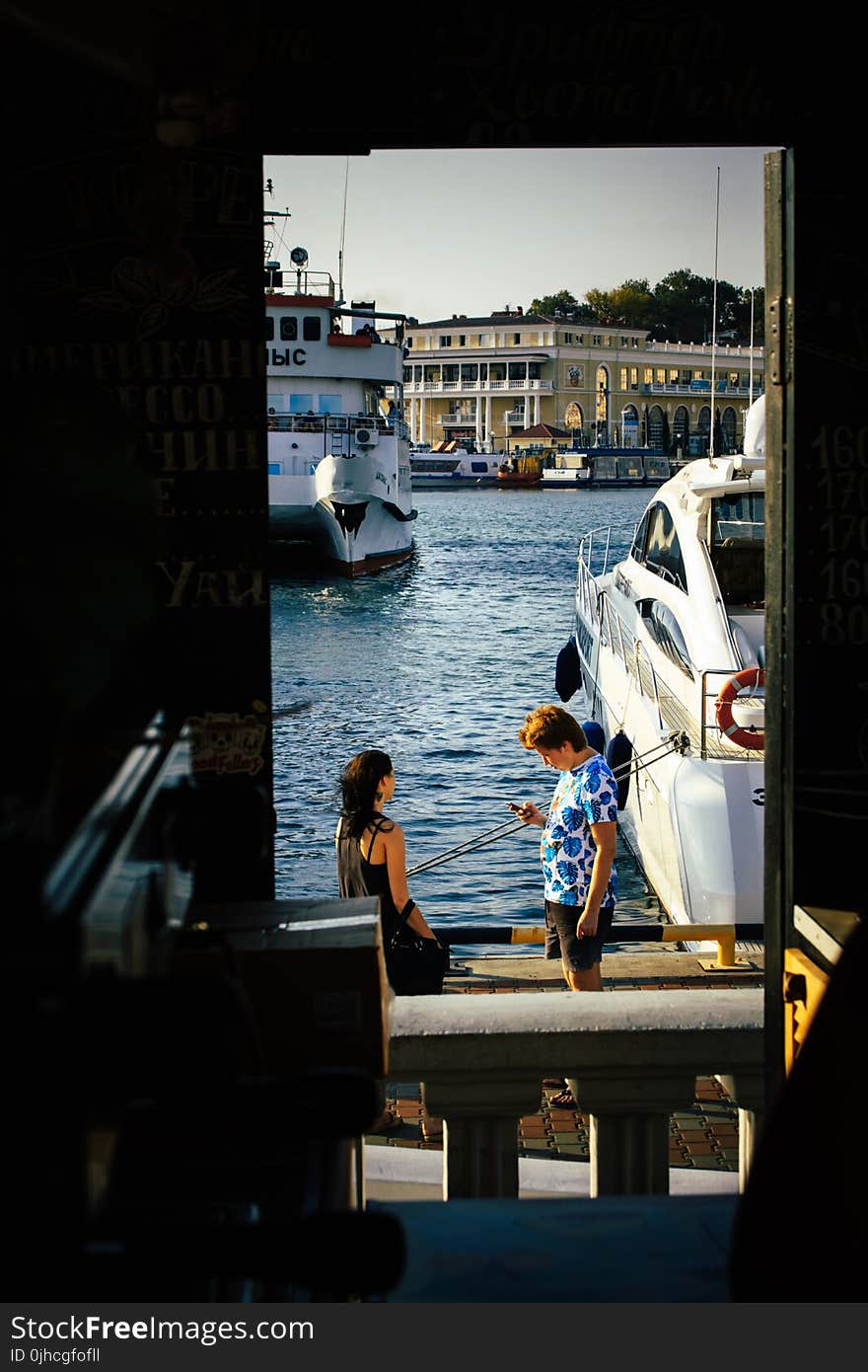 Man Standing Beside Woman Near White Yacht