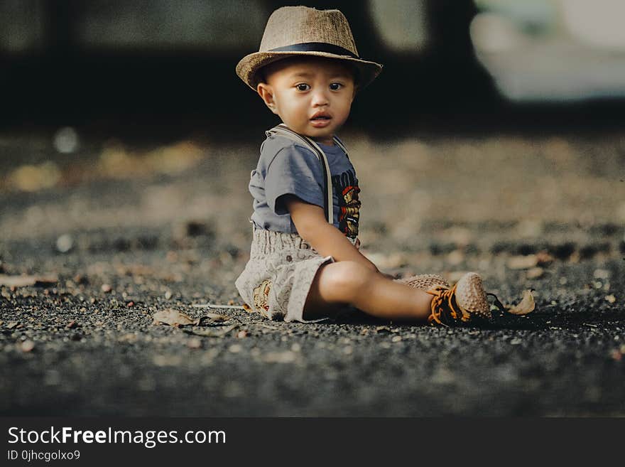 Child In Grey Shorts Sitting On Road