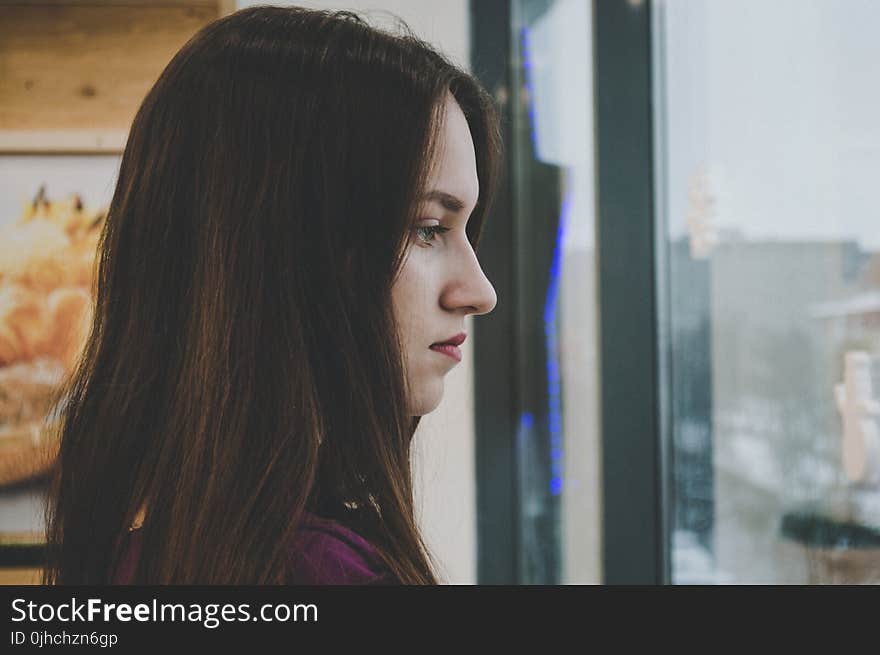 Photography of a Woman Looking Outside the Window