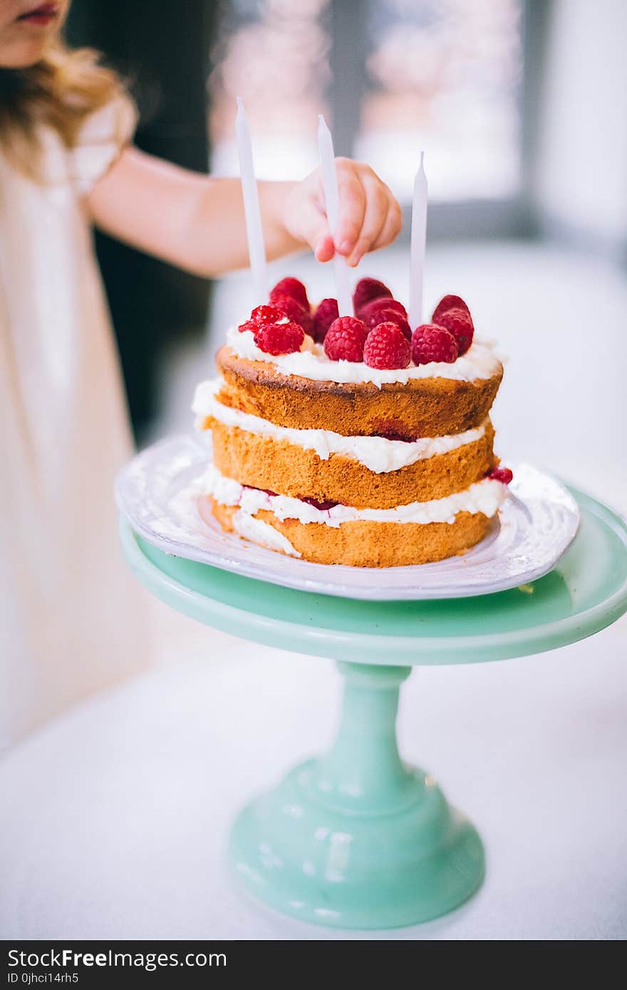 Girl Putting a Candle on 3-layered Cake