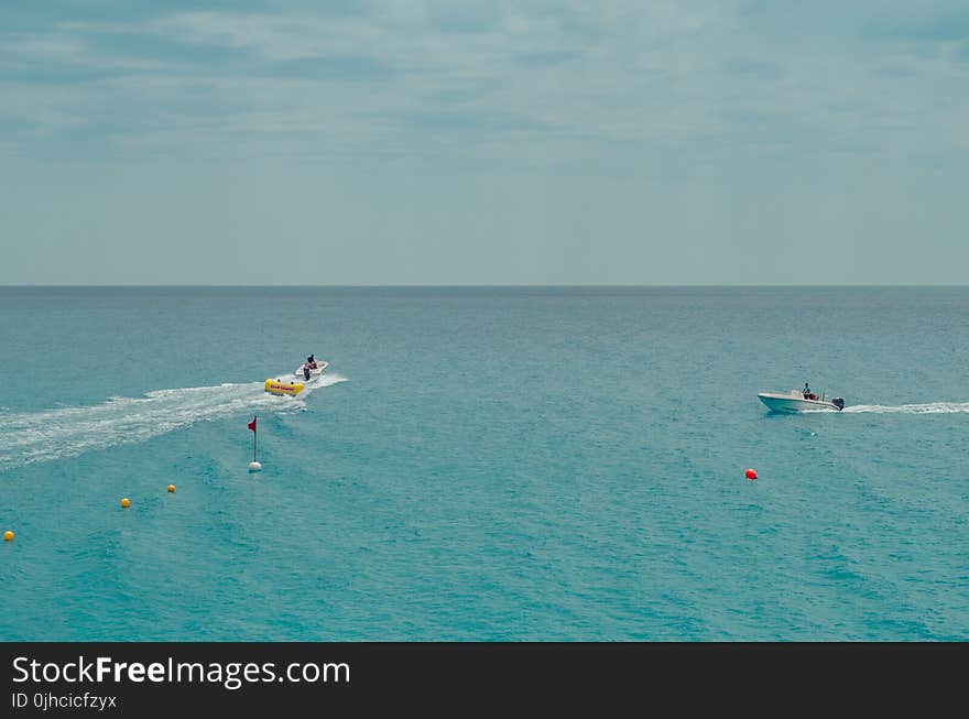 Two People Rides Watercrafts On Body Of Water Under Clear Blue Sky