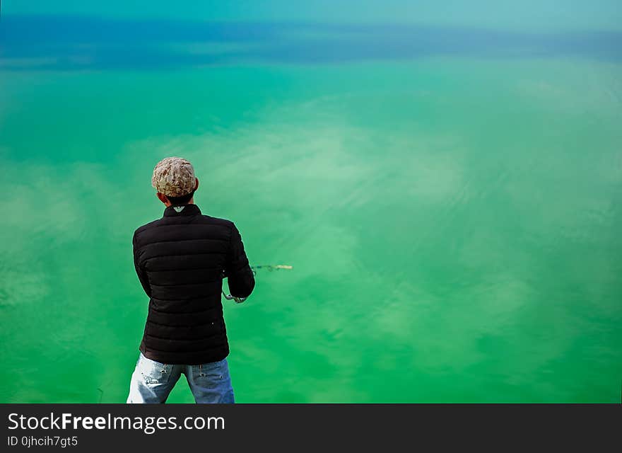 Man in Black Jacket Standing in Front of Sea