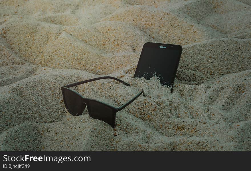 Photo of Phone and Sunglasses on Sand