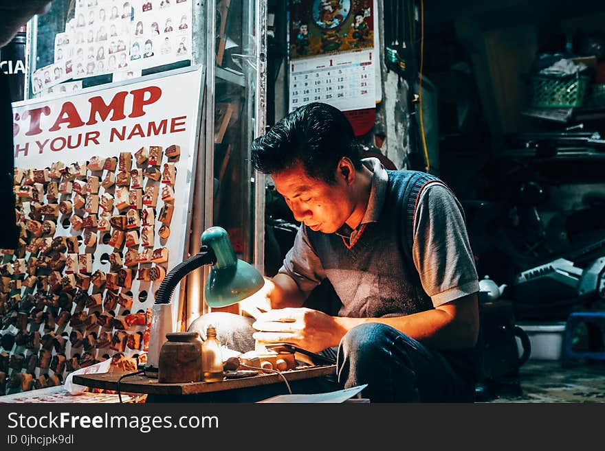 Man Holding Handheld Tool on Desk With Lamp