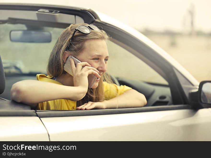 Blonde-haired Woman in Yellow T-shirt Wearing Black Sunglasses Holding Silver Smartphone