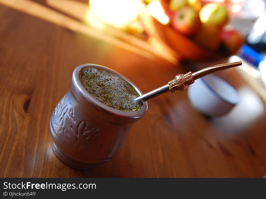 Silver-colored Teacup With Stirrer on Brown Wooden Table