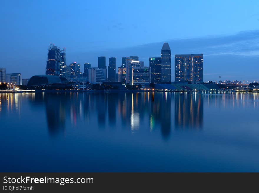 City Buildings Beside Body Of Water During Night Time