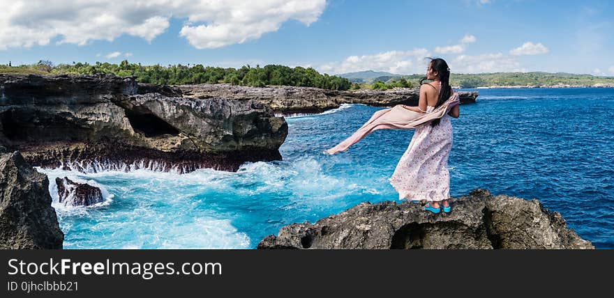 Photography of Woman Standing on Rock in Front of Sea