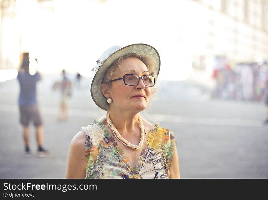 Depth of Field Photography of Woman in Pastel Color Sleeveless Shirt and White Sunhat