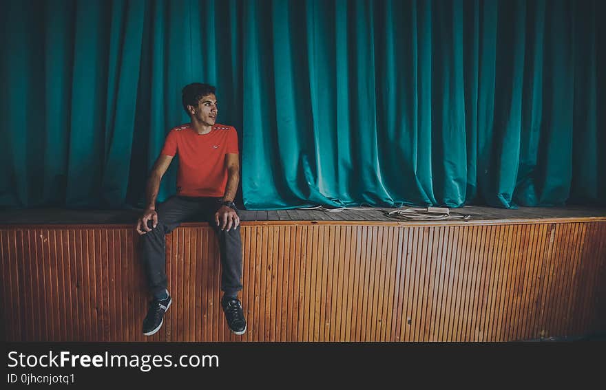 Man on Red Crew-neck T-shirt Sitting on Stage