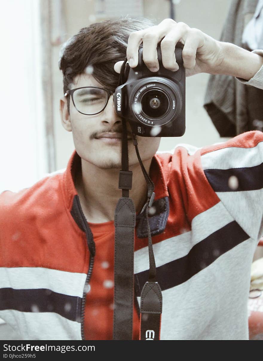 Man in Red and White Full-zip Jacket Holding Canon Dslr Camera