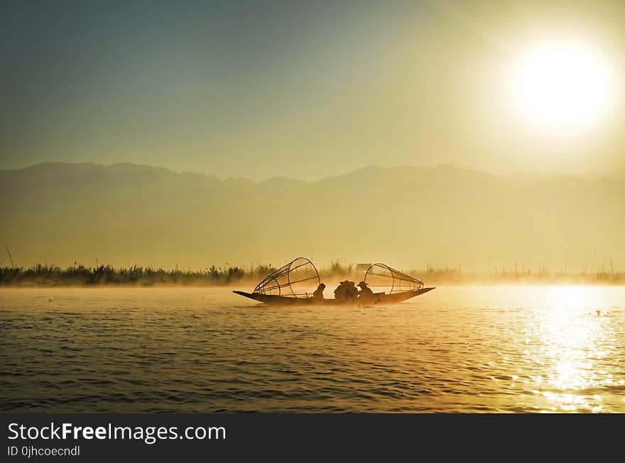 Group of People Riding Boat in the Middle of Water during Sunrise